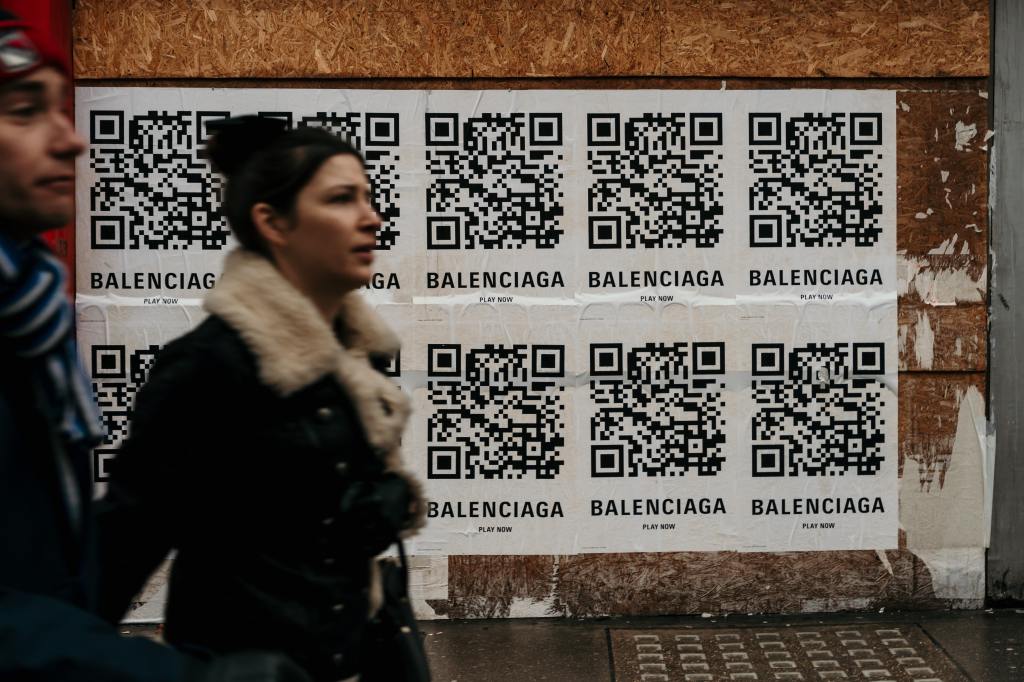Male and female walking past a wall of QR codes.