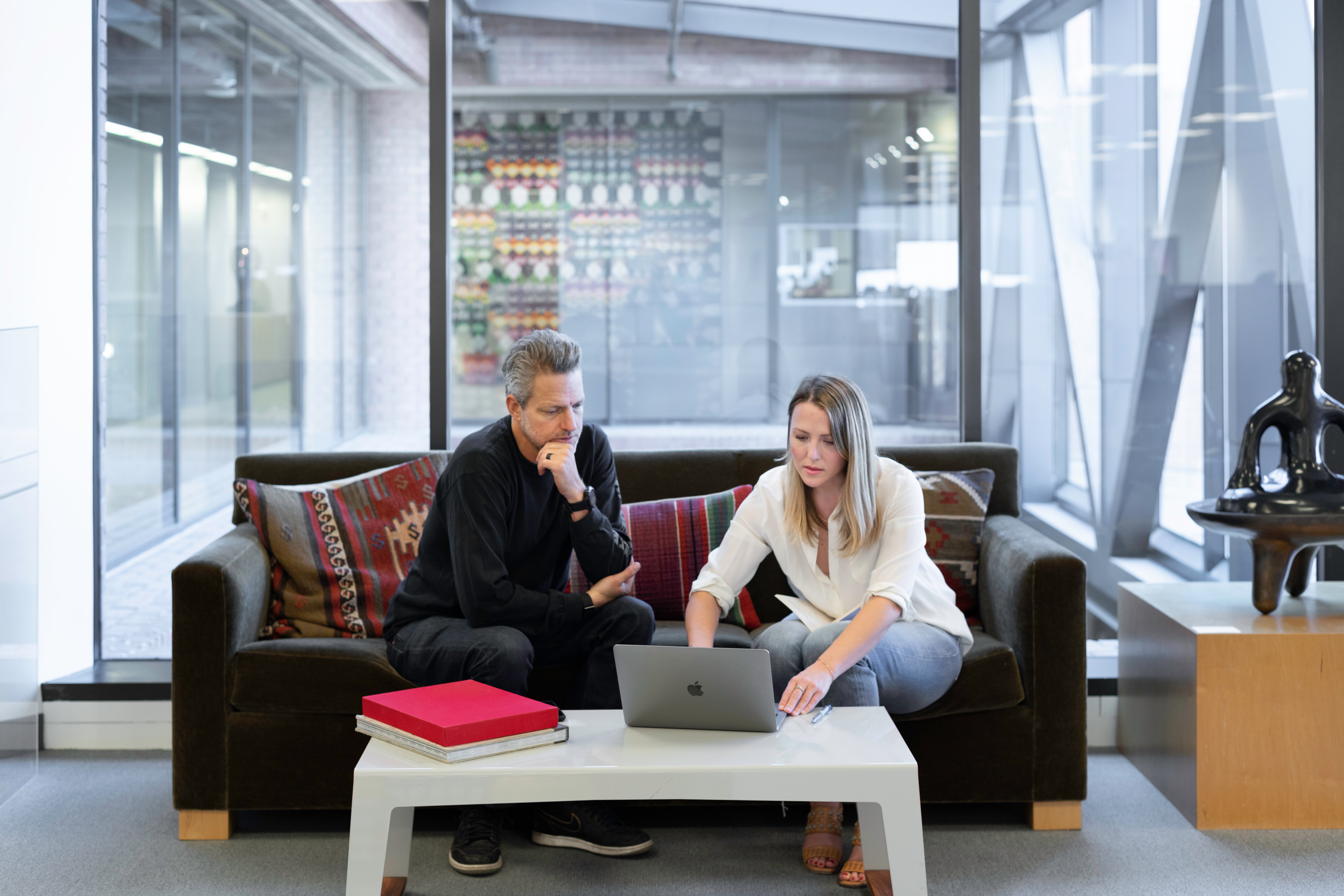 Man and woman sat on sofa looking at laptop computer.