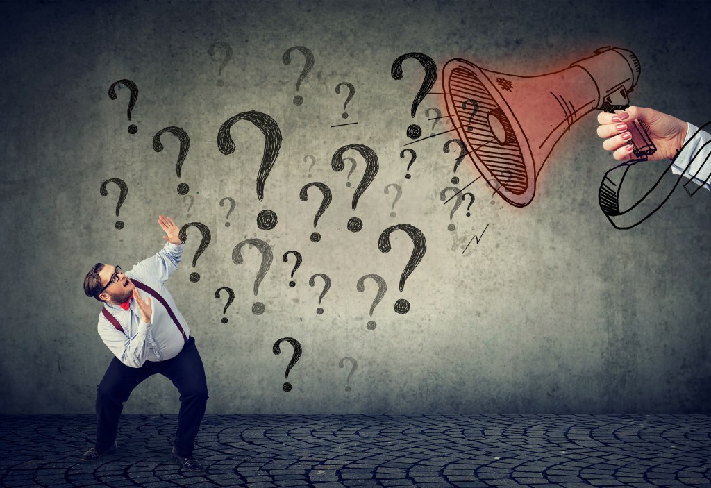 Frightened man being asked many questions through a megaphone.