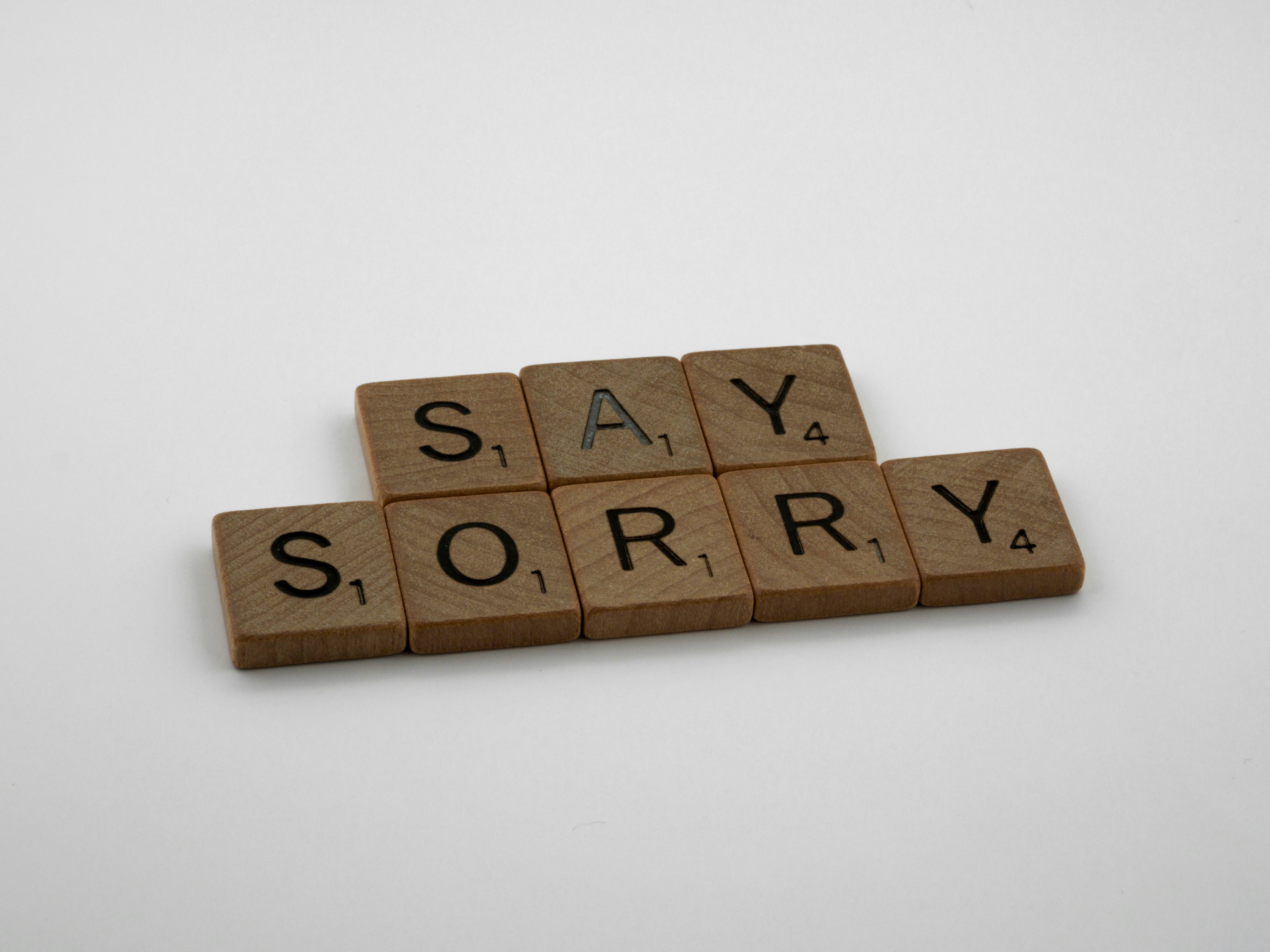Scrabble tiles spelling out 'Say Sorry.'