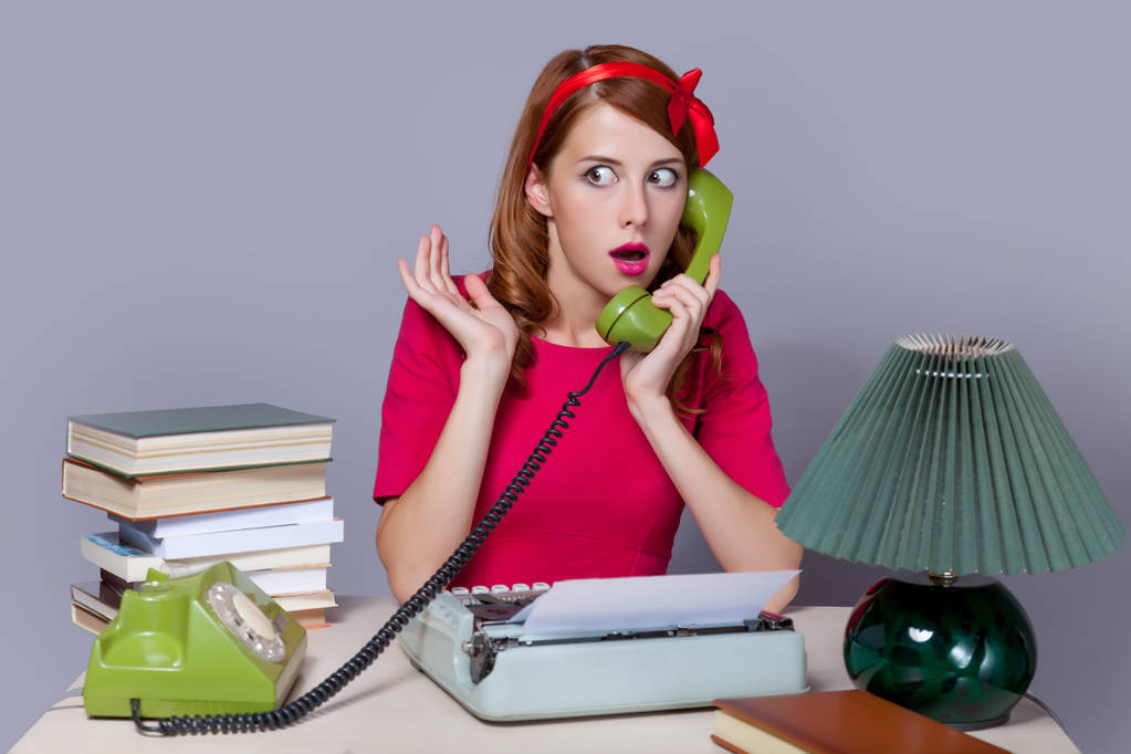 Woman at typewriter on telephone.