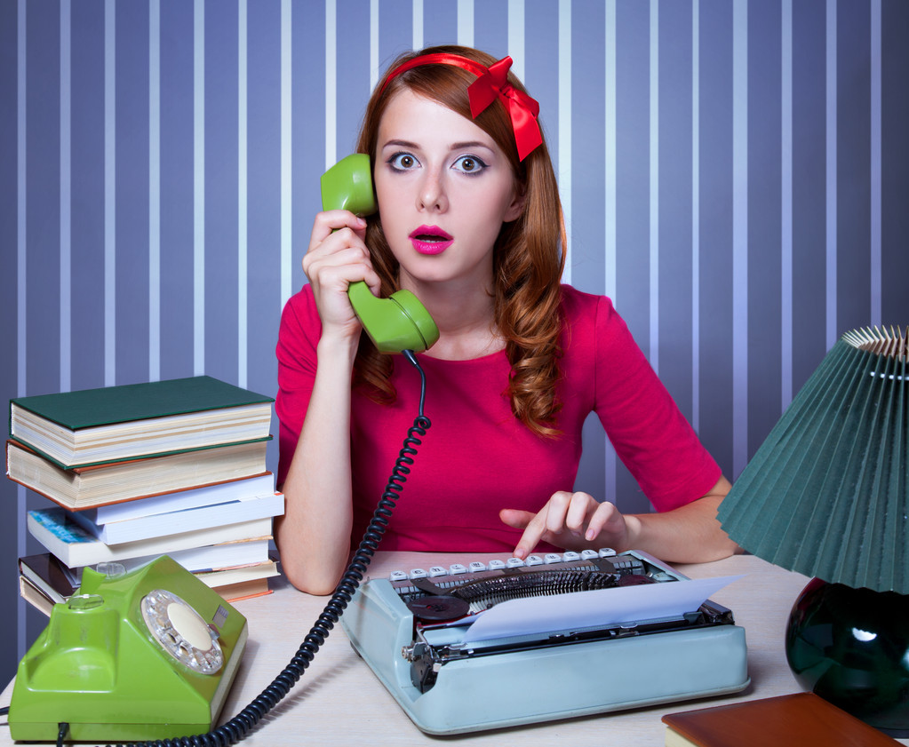 Woman at typewriter on telephone.